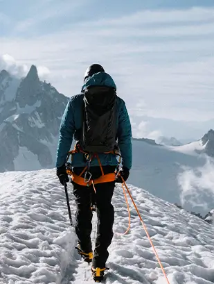 A climber walking a snowy ridge