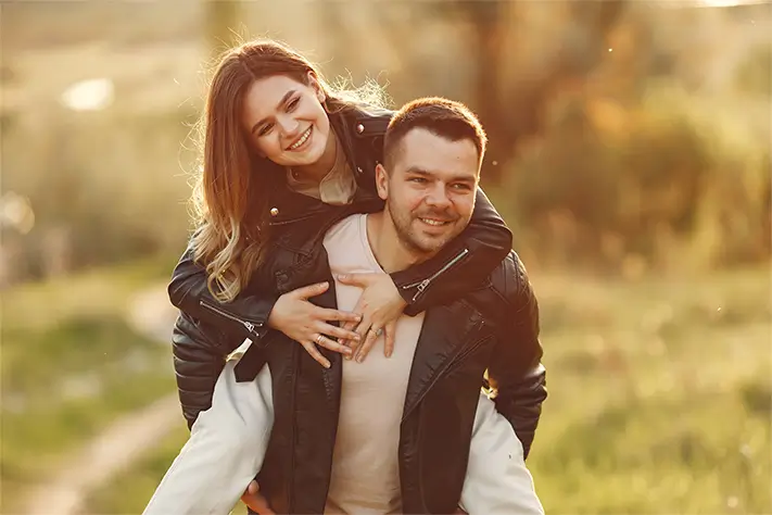 A smiling couple outdoors in the sun.
